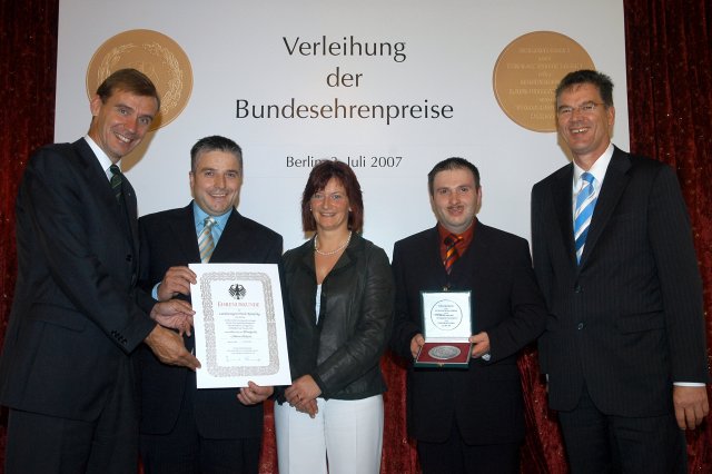 DLG-Präsident Carl-Albrecht Bartmer (links) überreicht gemeinsam mit dem Parlamentarischen Staatssekretär Dr. Gerd Müller (rechts) Urkunde und Medaille an das Inhaberehepaar Erich und Karola Kanefzky sowie Produktionsleiter Markus Deißer (2.v.r.).